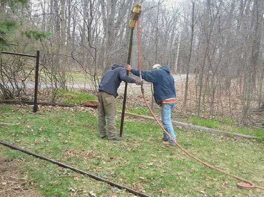 rhino pounder being used to drive a galvanized steel rod into the ground for a fence post