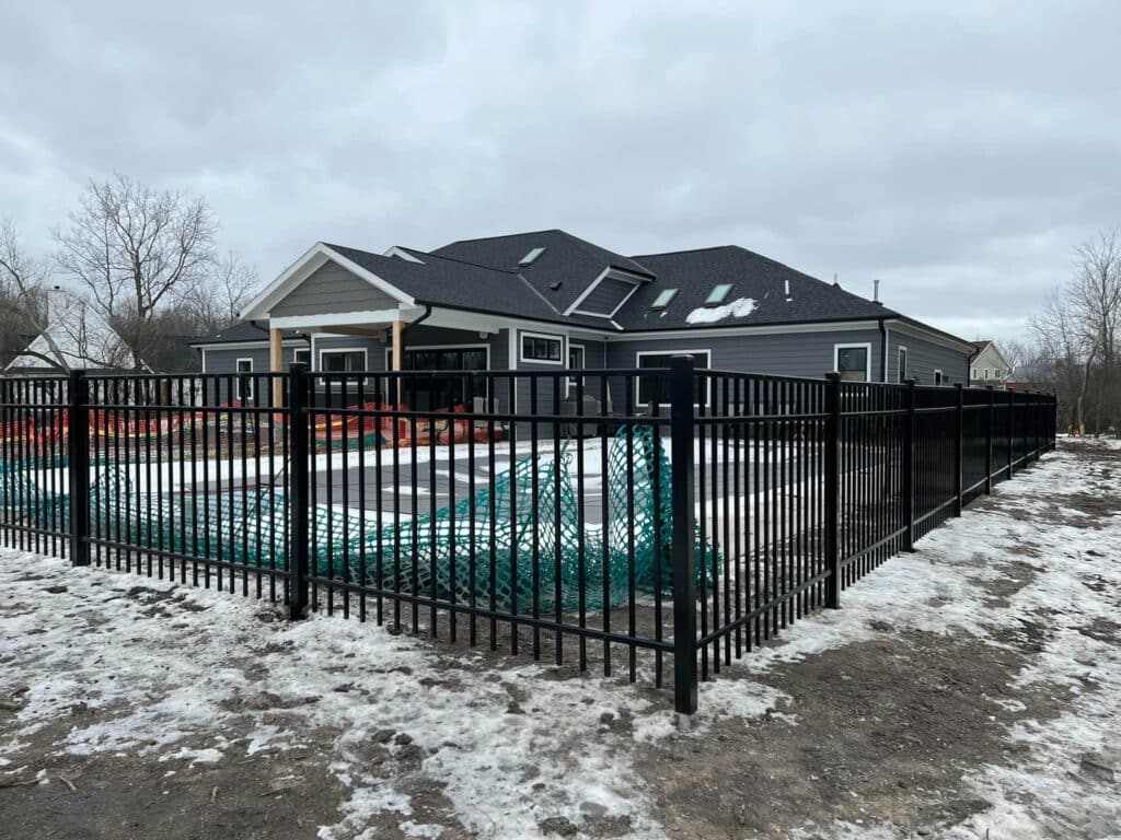 Photo of an aluminum fence installed with snow on the ground in the winter.