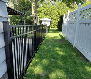 Completed aluminum fence installation on the left and neighboring completed vinyl installation on the right