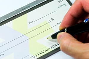 How Much Will a Fence Cost in 2023? Image of person signing a blank check.