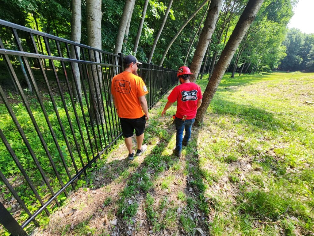 industrial aluminum fence in background with fence contractor walking alongside it