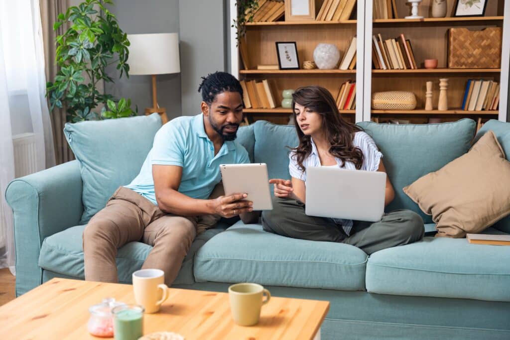 Couple sitting on couch searching line for the best fence company near me and evaluating their choices